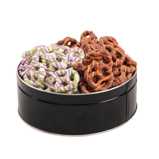 Two types of chocolate-covered pretzels in a round black metal tin, with one pretzel twisted in white and purple stripes and the other in dark and milk chocolate swirls.