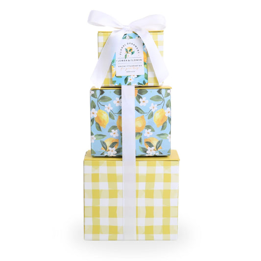 Stack of gift boxes with lemon-themed designs and a white ribbon on a white background