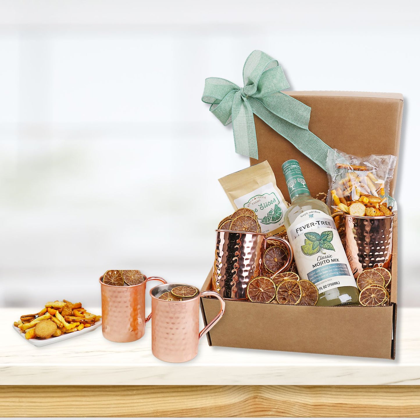 Gift box with drinks, snacks, and mugs on a white surface