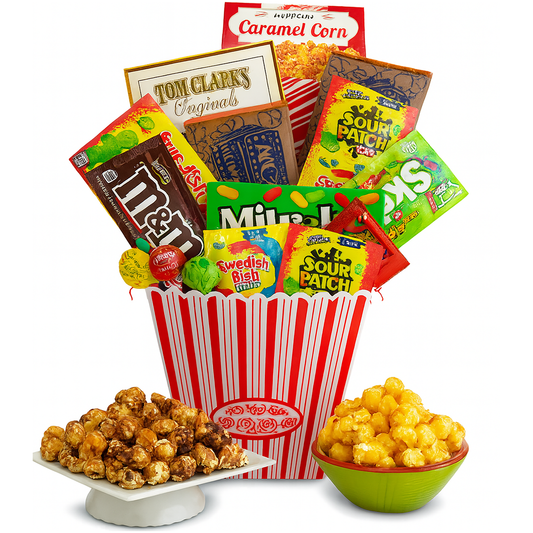 Assorted candy and popcorn in a red and white striped bucket on a white background