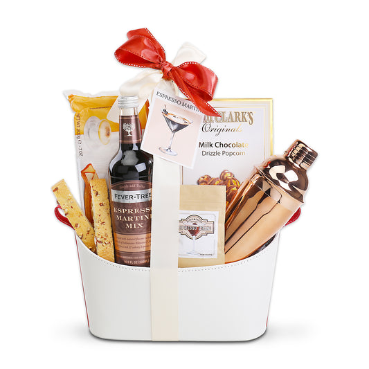 Gift basket with cocktail mix, shaker, and snacks on a white background