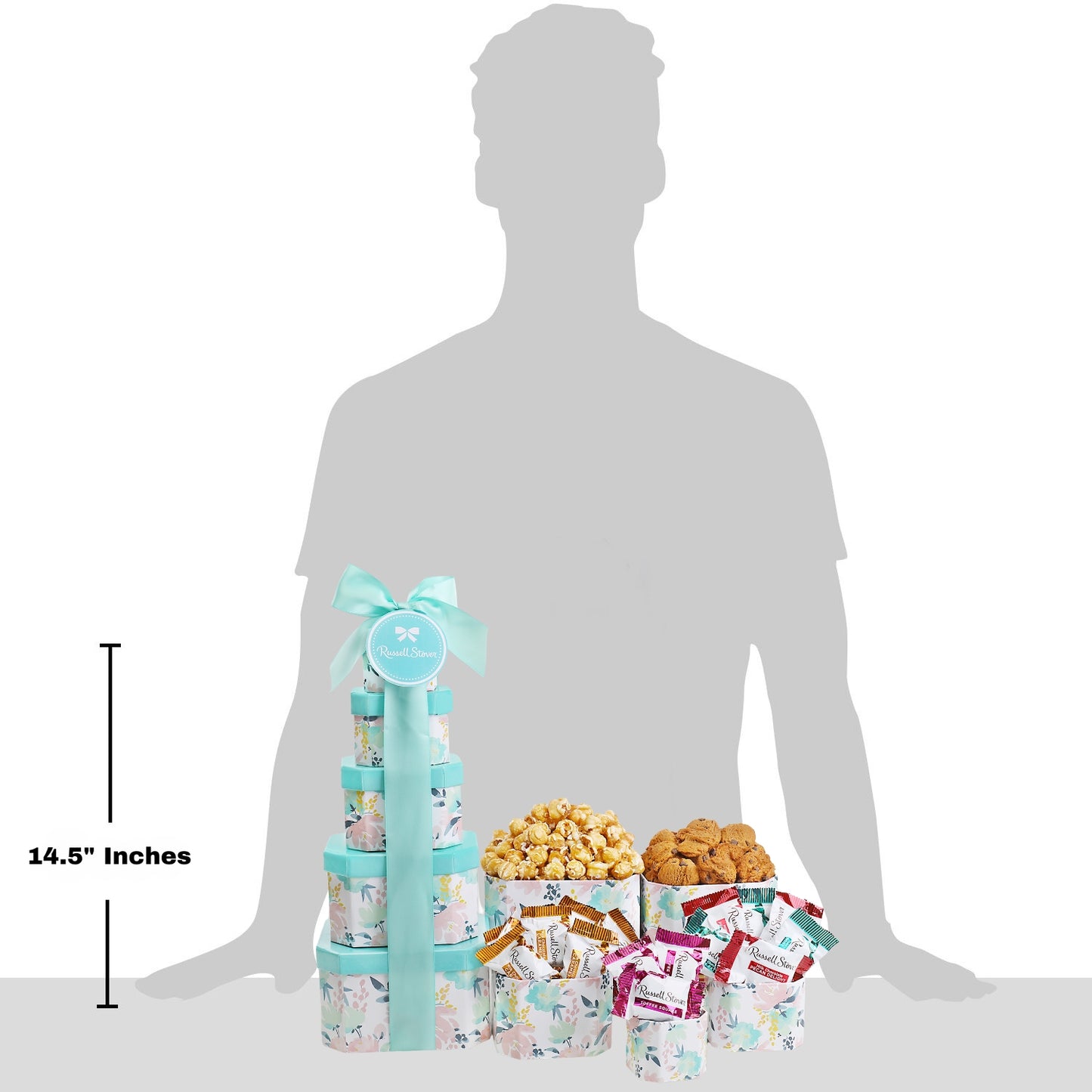 Gourmet gift tower with snacks and candies next to a silhouette of a person for scale.