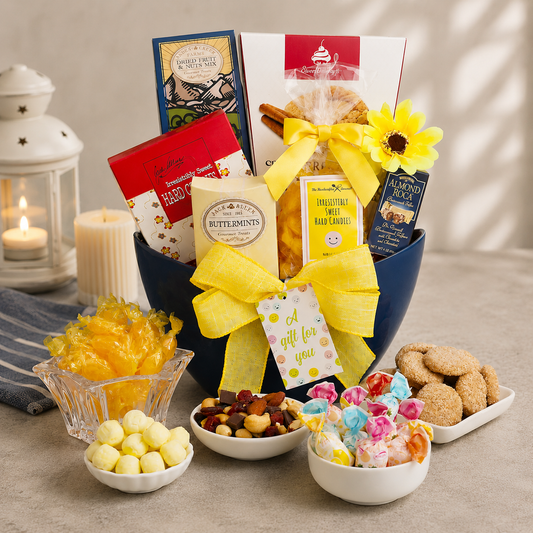 Gourmet gift basket with candies, cookies, and a candle on a wooden surface.