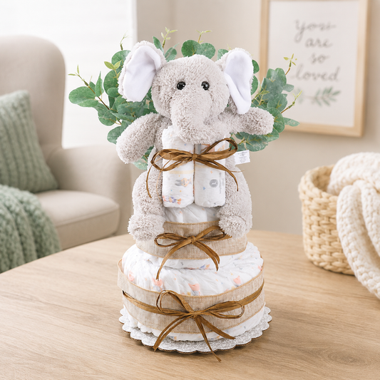 Decorative diaper cake with plush elephant toy on a wooden table.