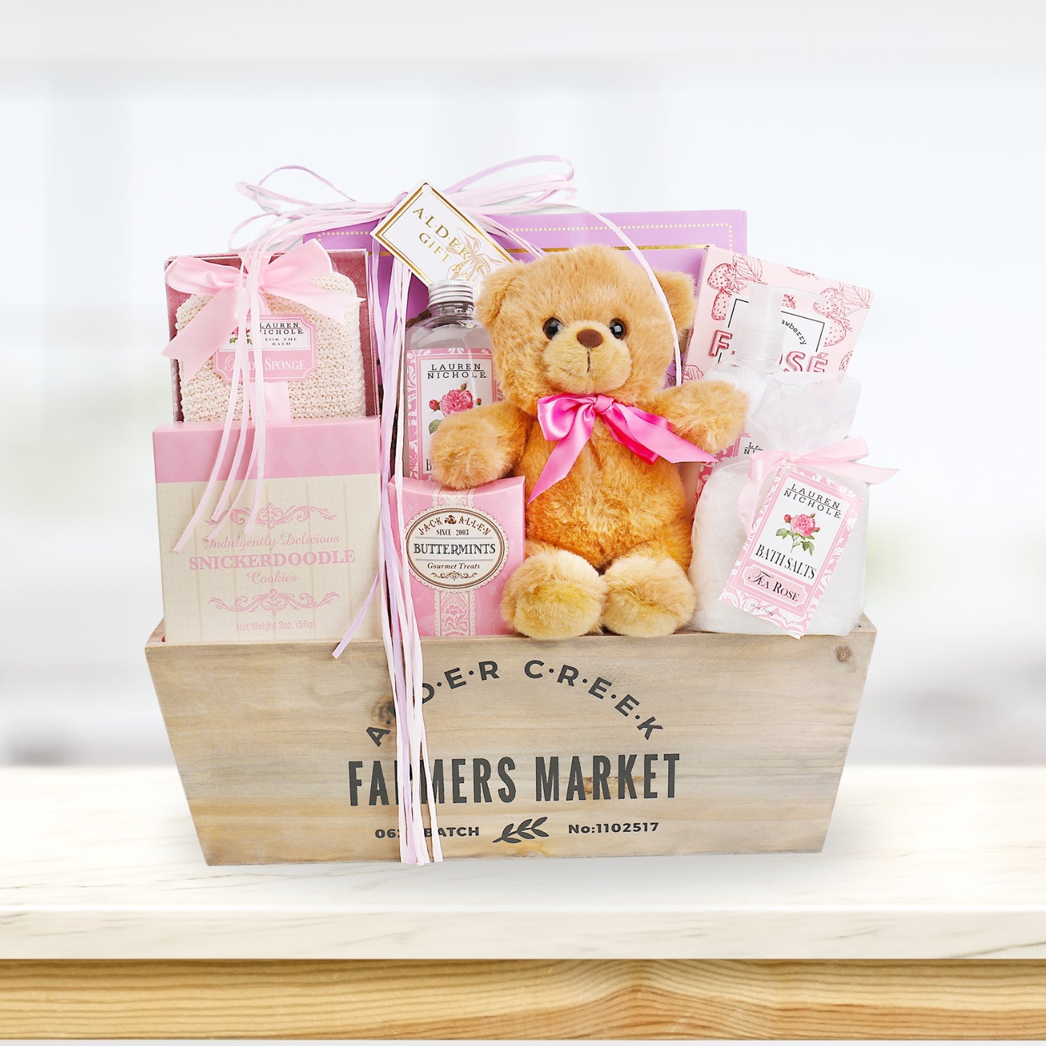 Gift basket with teddy bear, bath products, and other items on a white background