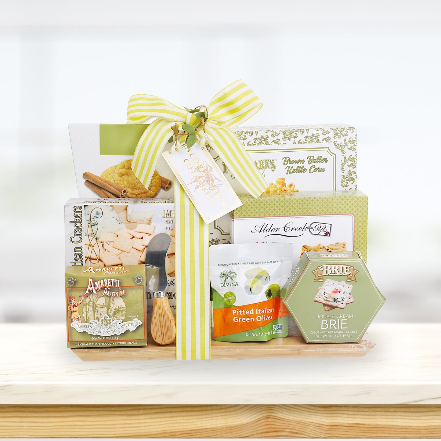 Gift basket with crackers, olives, and cheese on a wooden surface with a white background