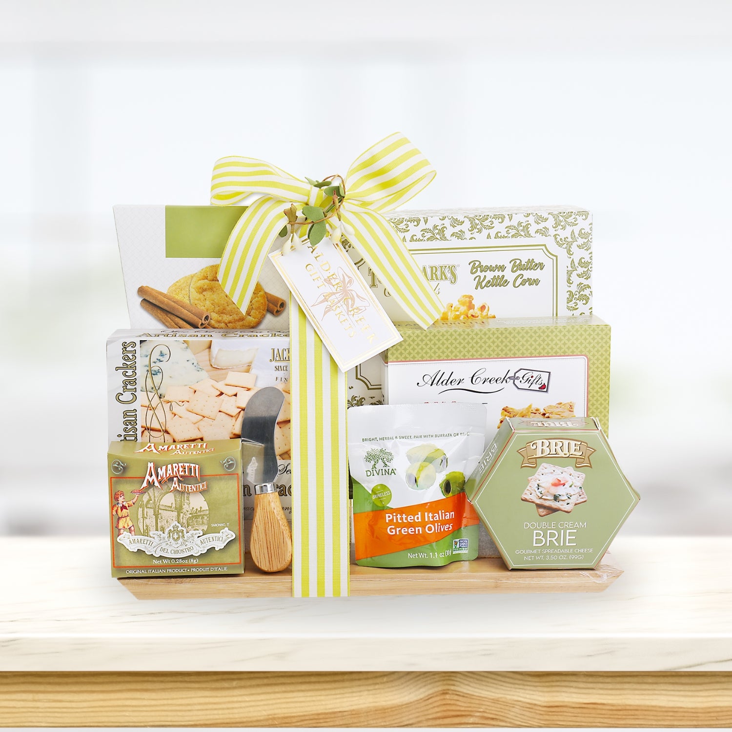 Gift basket with crackers, olives, and cheese on a wooden surface with a white background